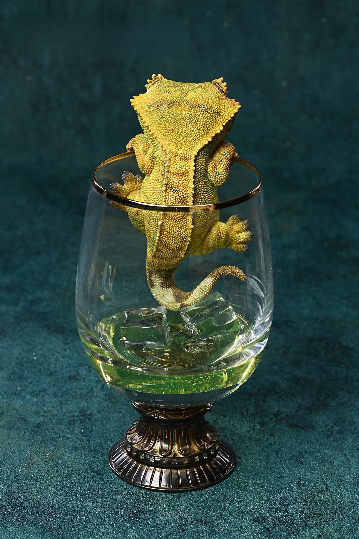 A realistic 1/1 scale Eyelash Gecko figurine made of resin, perched on a glass cup with ice cubes, showcasing intricate textures and lifelike details, perfect for reptile collectors and wildlife lovers.