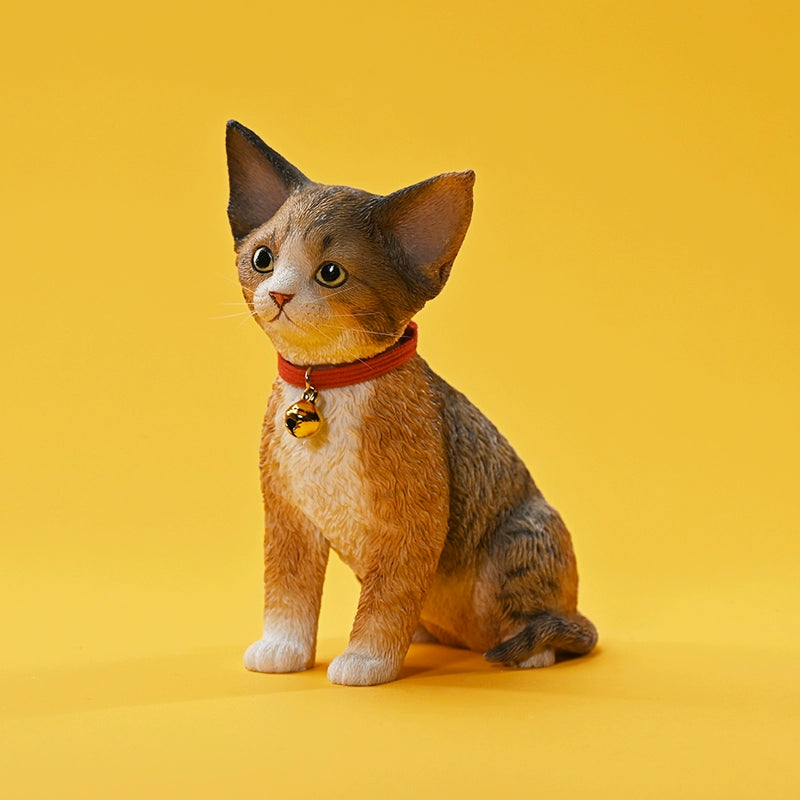 A set of 1/3 scale German Curly Cat resin models featuring five cats with distinct fur colors and patterns. The cats are shown sitting attentively around a pair of human legs, wearing red collars with bells. The scene is set against a yellow background.