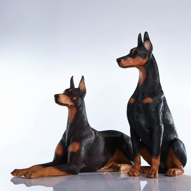 "A set of two 1/6 scale Doberman Pinscher resin models, one sitting and the other lying down, showcasing realistic details and noble posture."