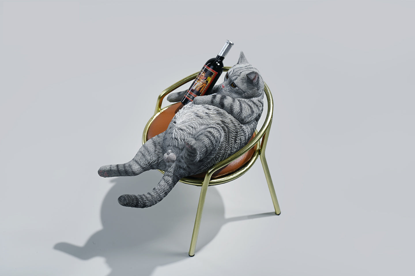 A 1/6 scale figurine of an orange tabby cat lounging on a chair with a bottle, portraying a humorous 'drunk' pose.