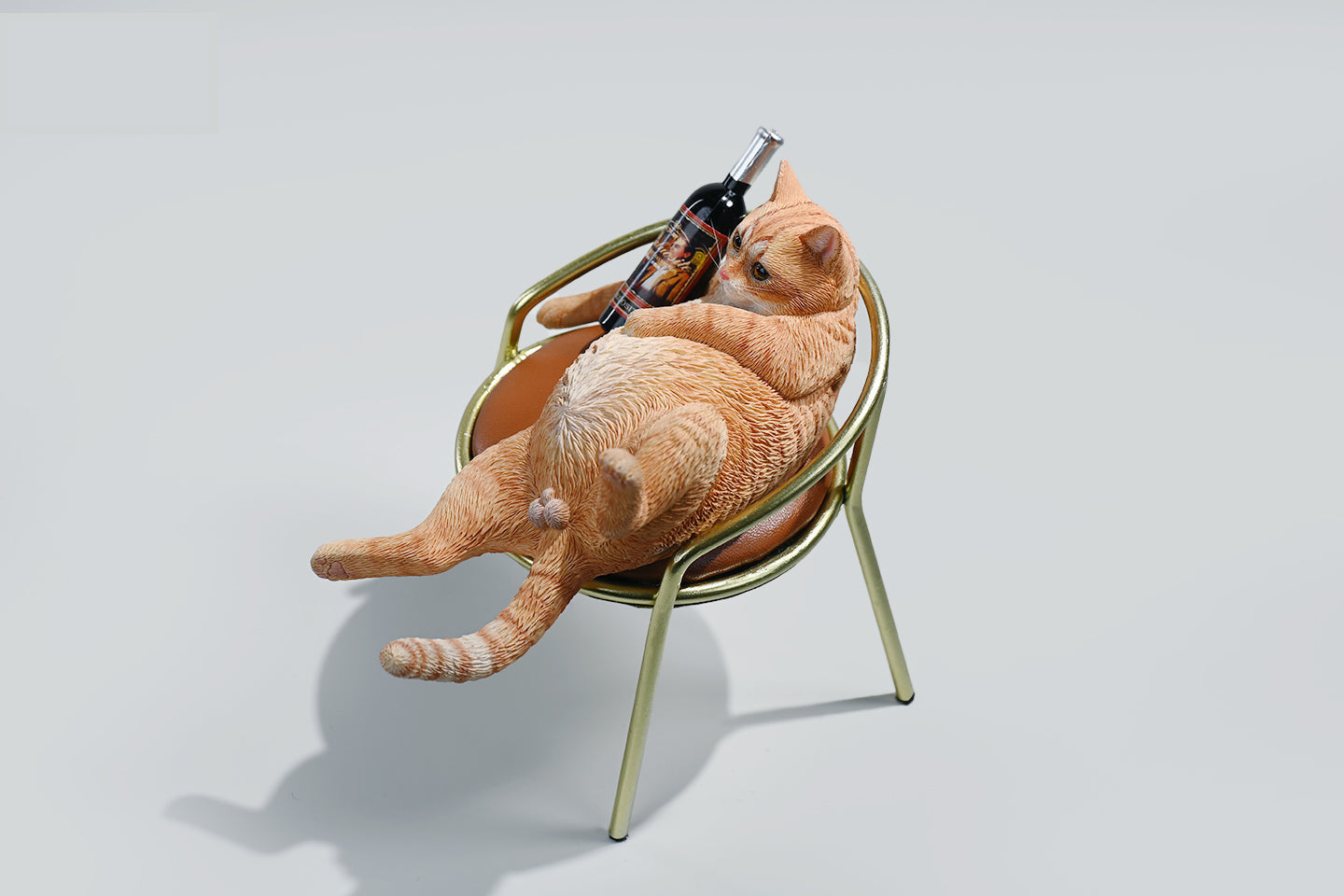 A 1/6 scale figurine of an orange tabby cat lounging on a chair with a bottle, portraying a humorous 'drunk' pose.