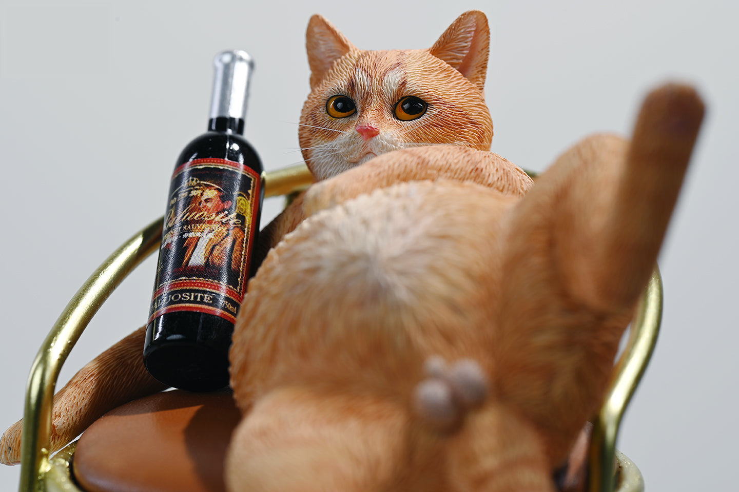 A 1/6 scale figurine of an orange tabby cat lounging on a chair with a bottle, portraying a humorous 'drunk' pose.