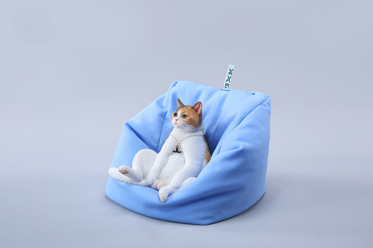 A set of four realistic 1/6 scale lazy cat figurines in different colors, each sitting comfortably with a lifelike expression. The cats are depicted in various coats: calico, grey tabby, orange tabby, and black. One figurine is shown lounging on a blue beanbag, adding to the whimsical charm of the collection.