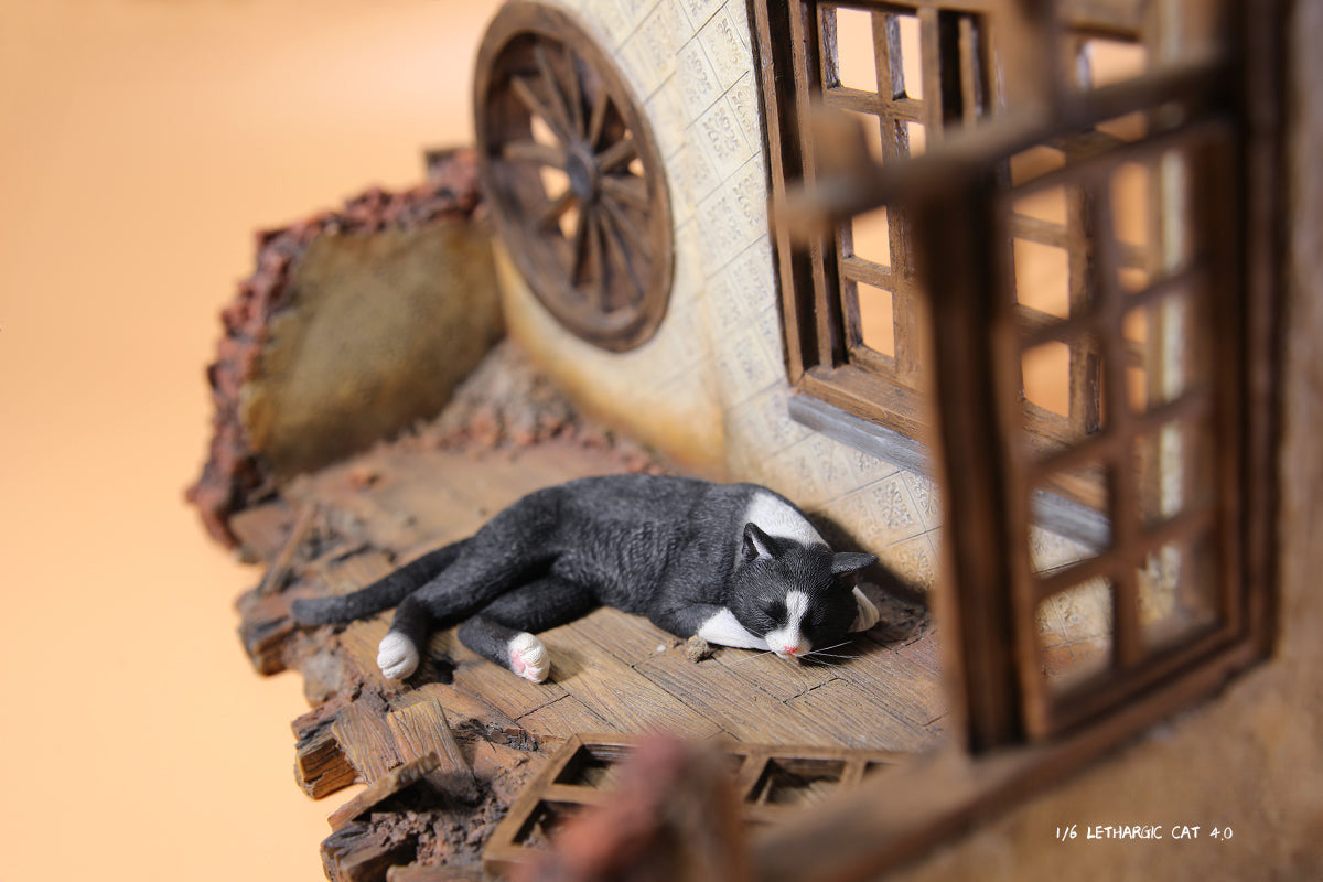 A realistic 1/6 scale model of a relaxed gray cat sleeping on a soft, gray couch, accompanied by two other cat figures lying nearby. The cat figures are detailed with life-like features, capturing their lazy and content postures, perfect for collectors and cat enthusiasts.