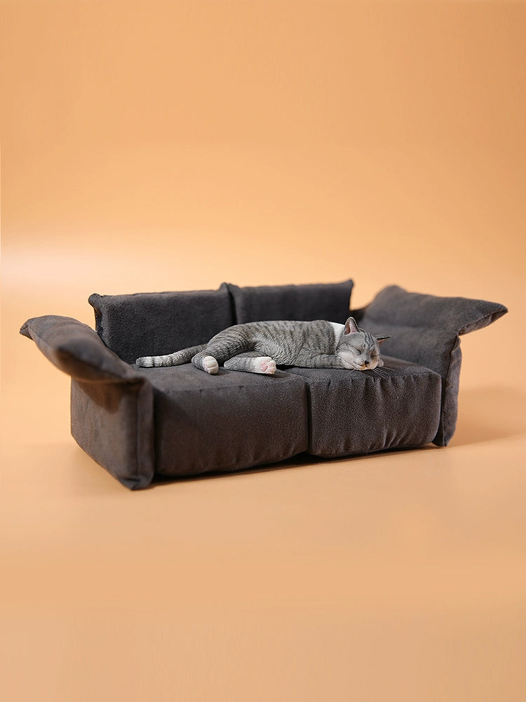 A realistic 1/6 scale model of a relaxed gray cat sleeping on a soft, gray couch, accompanied by two other cat figures lying nearby. The cat figures are detailed with life-like features, capturing their lazy and content postures, perfect for collectors and cat enthusiasts.