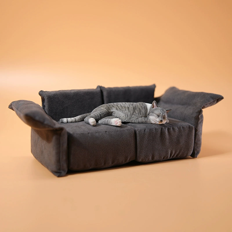 A realistic 1/6 scale model of a relaxed gray cat sleeping on a soft, gray couch, accompanied by two other cat figures lying nearby. The cat figures are detailed with life-like features, capturing their lazy and content postures, perfect for collectors and cat enthusiasts.