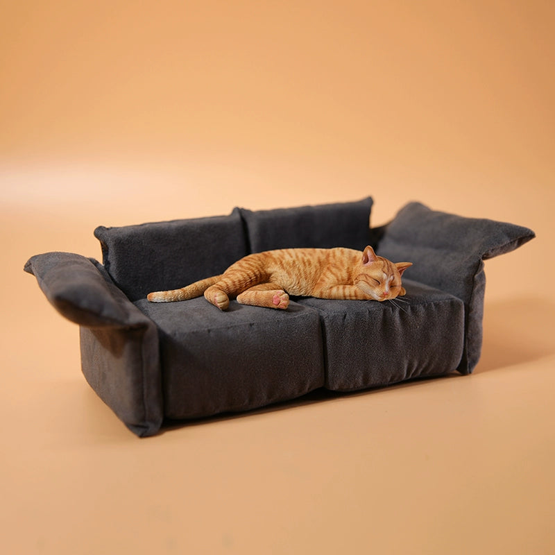 A realistic 1/6 scale model of a relaxed gray cat sleeping on a soft, gray couch, accompanied by two other cat figures lying nearby. The cat figures are detailed with life-like features, capturing their lazy and content postures, perfect for collectors and cat enthusiasts.