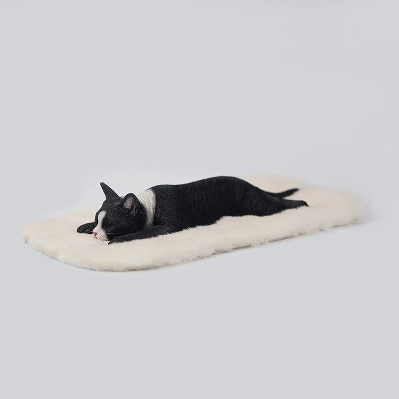 A detailed 1/6 scale resin model of a lephargic cat lying flat on its stomach. The cat, with realistic fur texture and relaxed pose, rests on a soft white pad. The model captures the essence of a sleepy, content cat.