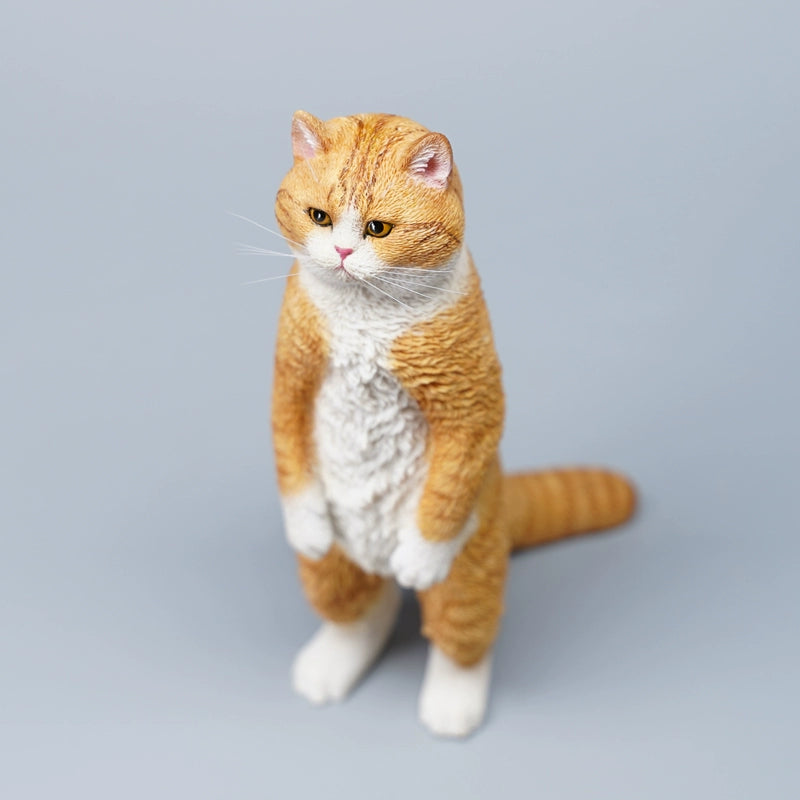 A collection of six detailed figurines of British Shorthair cats standing upright, showcasing a range of coat colors including grey, orange tabby, and black. The cats have expressive faces, with some sporting unique features like a white patch or striped fur. The figurines capture a playful and curious stance, each cat displaying a distinct personality.