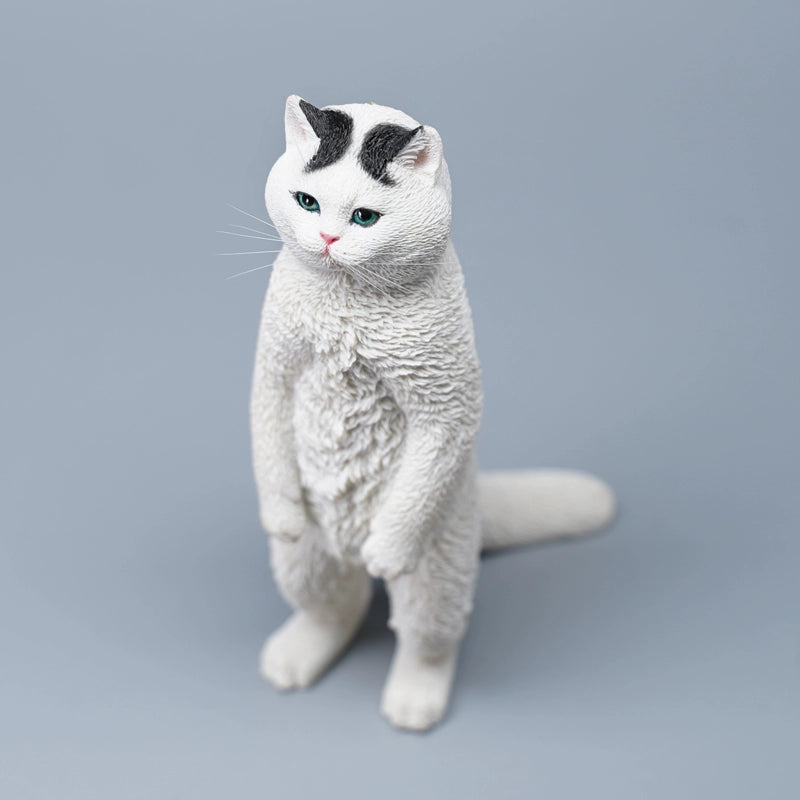 A collection of six detailed figurines of British Shorthair cats standing upright, showcasing a range of coat colors including grey, orange tabby, and black. The cats have expressive faces, with some sporting unique features like a white patch or striped fur. The figurines capture a playful and curious stance, each cat displaying a distinct personality.