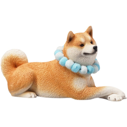 A collection of four Shiba Inu dog figurines in a prone position, each wearing a colorful pom-pom collar. The dogs, with diverse coat colors—white, tan, red, and black—are depicted lying down in a relaxed manner. The figurines are highly detailed, showcasing the breed's distinct features such as curled tails and alert expressions.