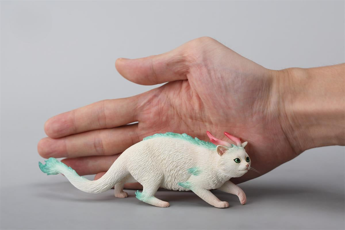 A highly detailed Catragon Figurine featuring a white feline with dragon-like features, including pastel green fur accents and delicate horns. This resin-crafted fantasy cat-dragon hybrid is an artistic and whimsical collectible. Ideal for display or as a gift for cat lovers and fantasy enthusiasts.