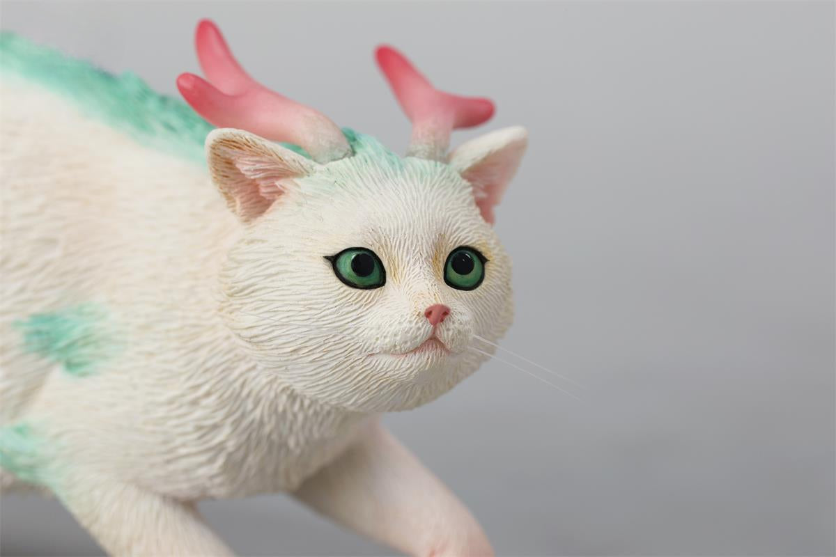 A highly detailed Catragon Figurine featuring a white feline with dragon-like features, including pastel green fur accents and delicate horns. This resin-crafted fantasy cat-dragon hybrid is an artistic and whimsical collectible. Ideal for display or as a gift for cat lovers and fantasy enthusiasts.