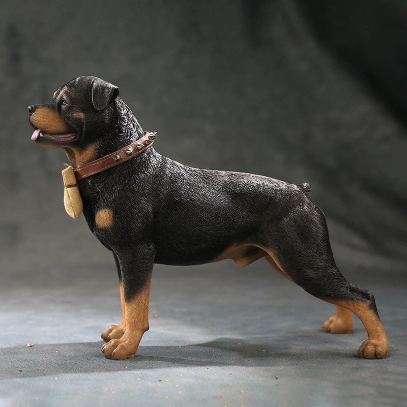 Three intricately detailed Rottweiler dog figurines stand on a grey surface. The figures exhibit lifelike features, from their distinct fur textures to the expressive faces. One wears a spiked collar with a small beige pouch, adding a touch of personality. The lighting emphasizes their muscular build and attentive expressions, making these resin models a perfect representation of the strong and loyal breed.