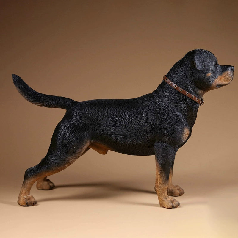 Three intricately detailed Rottweiler dog figurines stand on a grey surface. The figures exhibit lifelike features, from their distinct fur textures to the expressive faces. One wears a spiked collar with a small beige pouch, adding a touch of personality. The lighting emphasizes their muscular build and attentive expressions, making these resin models a perfect representation of the strong and loyal breed.