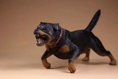 Three intricately detailed Rottweiler dog figurines stand on a grey surface. The figures exhibit lifelike features, from their distinct fur textures to the expressive faces. One wears a spiked collar with a small beige pouch, adding a touch of personality. The lighting emphasizes their muscular build and attentive expressions, making these resin models a perfect representation of the strong and loyal breed.