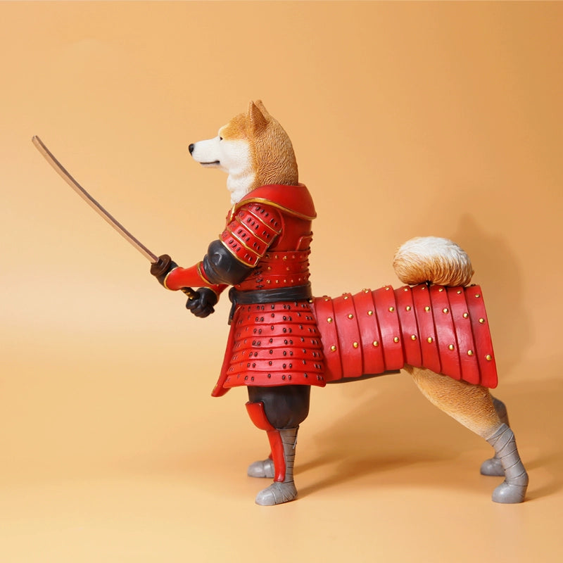 A set of two Shiba Inu figurines dressed as samurai warriors, showcasing intricate red armor details. One figurine is standing with a samurai sword, and the other is sitting, wearing a small yellow hat. The detailed armor features gold and black embellishments, adding a realistic and artistic touch to the figurines. Perfect for collectors and dog lovers alike.