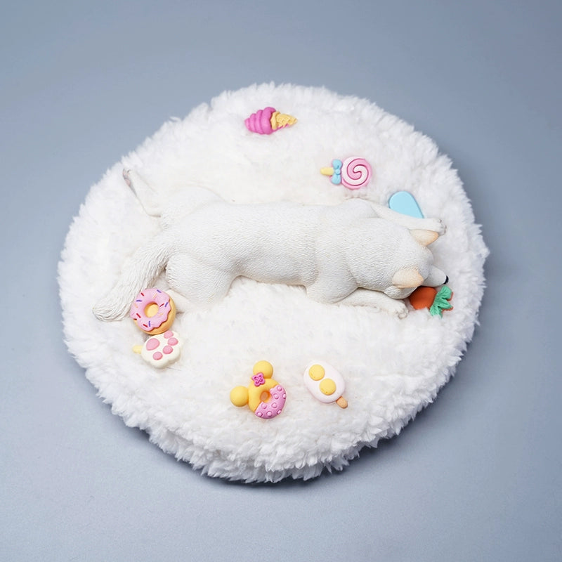 A detailed resin model of a sleeping Shiba Inu dog on a fluffy white bed, surrounded by colorful toy replicas like a carrot, ice cream cone, donut, and paw print. The model captures the serene essence of a Shiba Inu with its realistic fur texture and lifelike posture, ideal for collectors and dog enthusiasts.