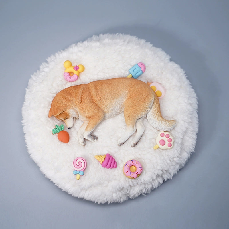 A detailed resin model of a sleeping Shiba Inu dog on a fluffy white bed, surrounded by colorful toy replicas like a carrot, ice cream cone, donut, and paw print. The model captures the serene essence of a Shiba Inu with its realistic fur texture and lifelike posture, ideal for collectors and dog enthusiasts.