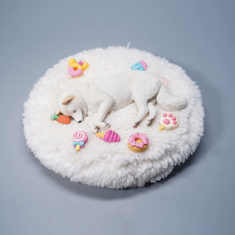 A detailed resin model of a sleeping Shiba Inu dog on a fluffy white bed, surrounded by colorful toy replicas like a carrot, ice cream cone, donut, and paw print. The model captures the serene essence of a Shiba Inu with its realistic fur texture and lifelike posture, ideal for collectors and dog enthusiasts.