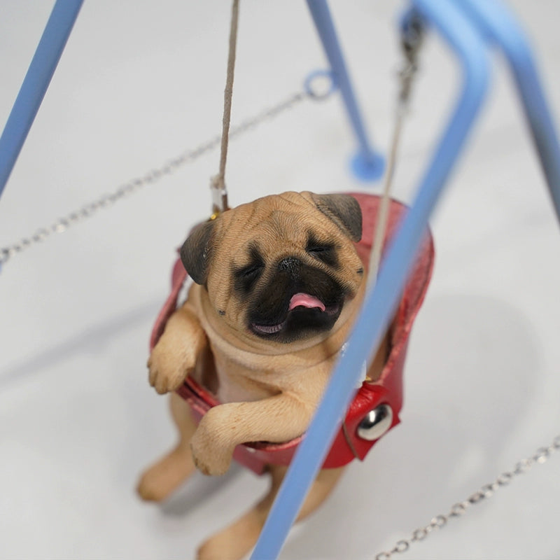 "1/6 scale pug dog figurines sitting in a red swing. These adorable and realistic models capture the playful nature of pugs, featuring lifelike details such as expressive faces and intricate fur textures. Ideal for dog lovers and collectors, these figurines add a touch of charm to any decor."