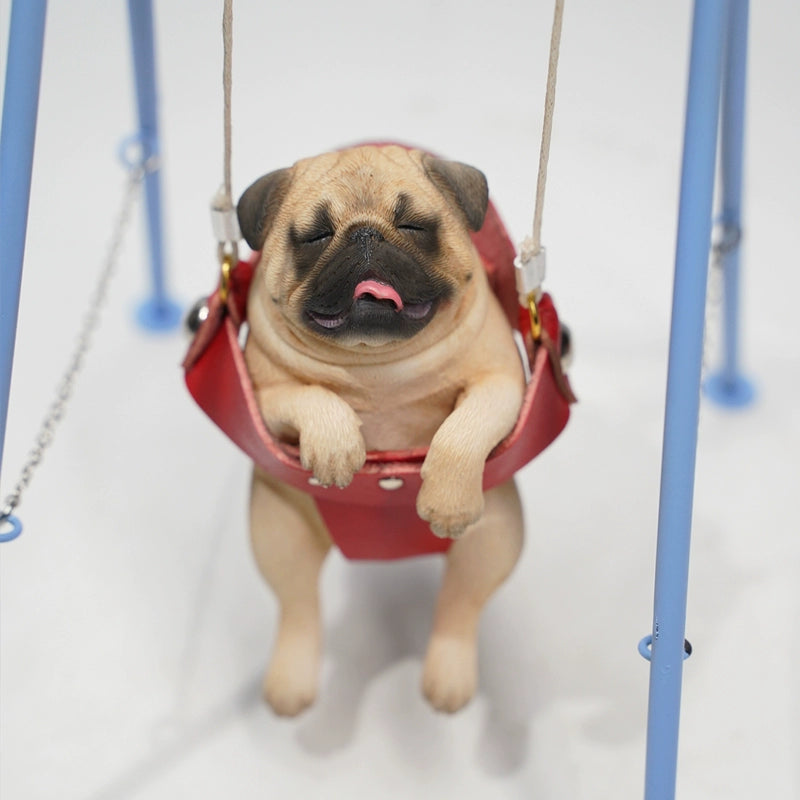 "1/6 scale pug dog figurines sitting in a red swing. These adorable and realistic models capture the playful nature of pugs, featuring lifelike details such as expressive faces and intricate fur textures. Ideal for dog lovers and collectors, these figurines add a touch of charm to any decor."