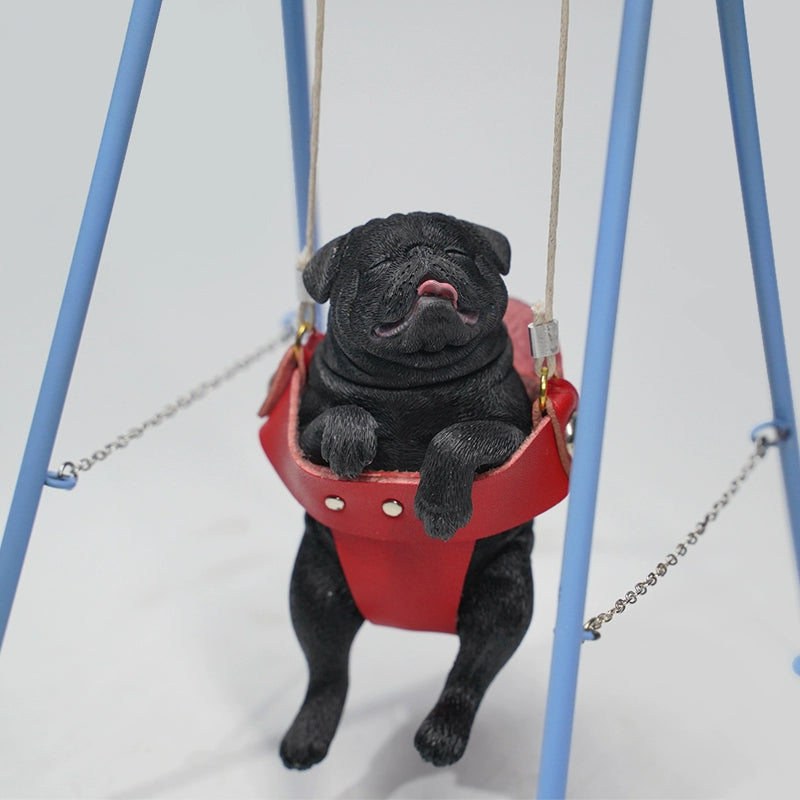 "1/6 scale pug dog figurines sitting in a red swing. These adorable and realistic models capture the playful nature of pugs, featuring lifelike details such as expressive faces and intricate fur textures. Ideal for dog lovers and collectors, these figurines add a touch of charm to any decor."