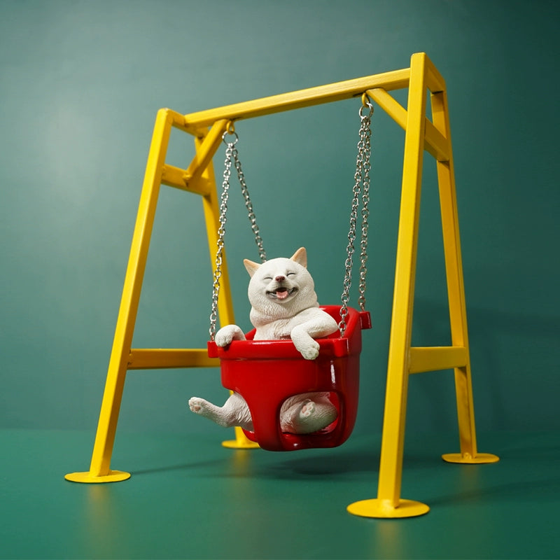 1/6 scale Shiba Inu dog figurines sitting in a red swing, mounted on a yellow frame. These lifelike models feature the cheerful expressions of Shiba Inus, detailed fur textures, and adorable poses. Perfect for collectors and dog lovers, these figurines bring a touch of playfulness and charm to any display setting.