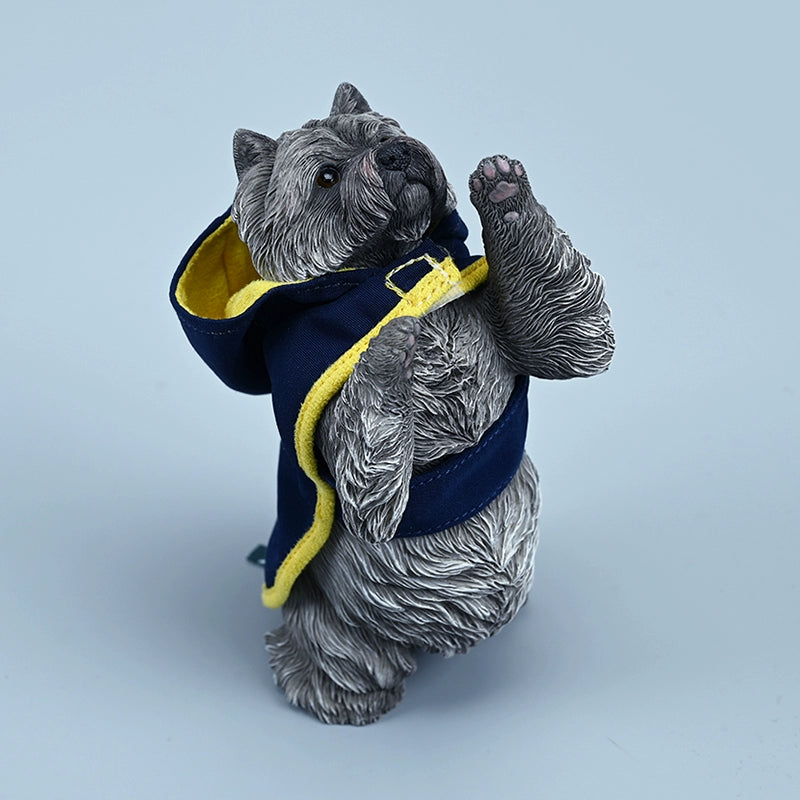 A figurine of a West Highland White Terrier standing on its hind legs, dressed in a blue hoodie with yellow trim. The detailed and lifelike model captures the dog's playful and curious nature, making it an adorable addition to any collection.