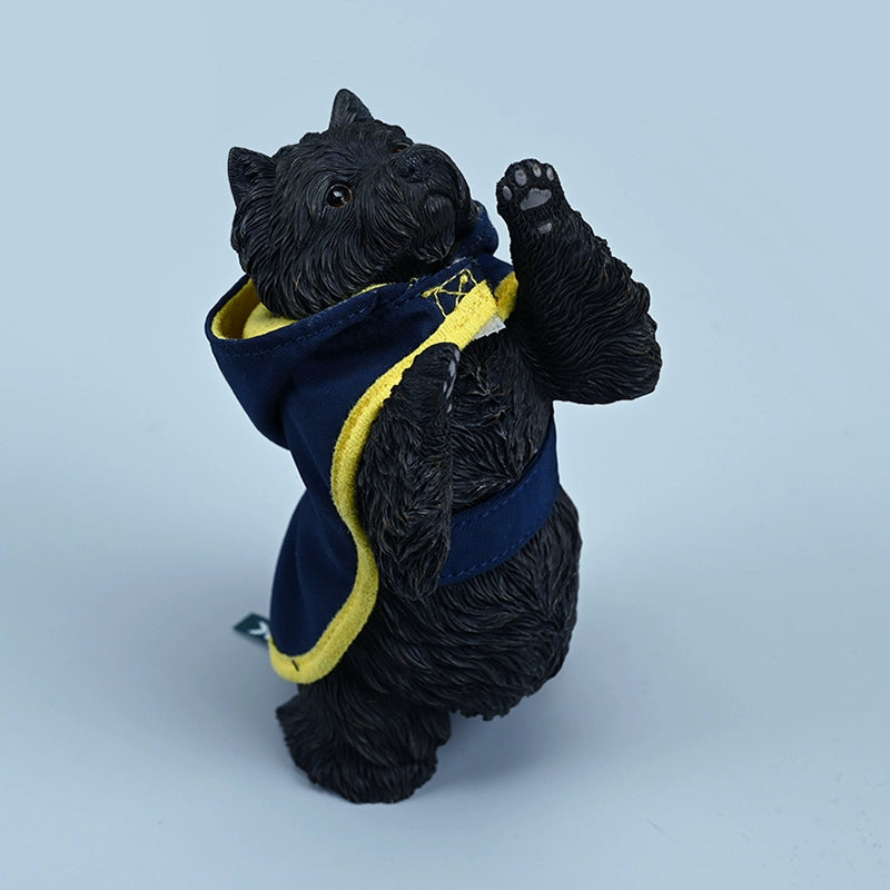 A figurine of a West Highland White Terrier standing on its hind legs, dressed in a blue hoodie with yellow trim. The detailed and lifelike model captures the dog's playful and curious nature, making it an adorable addition to any collection.