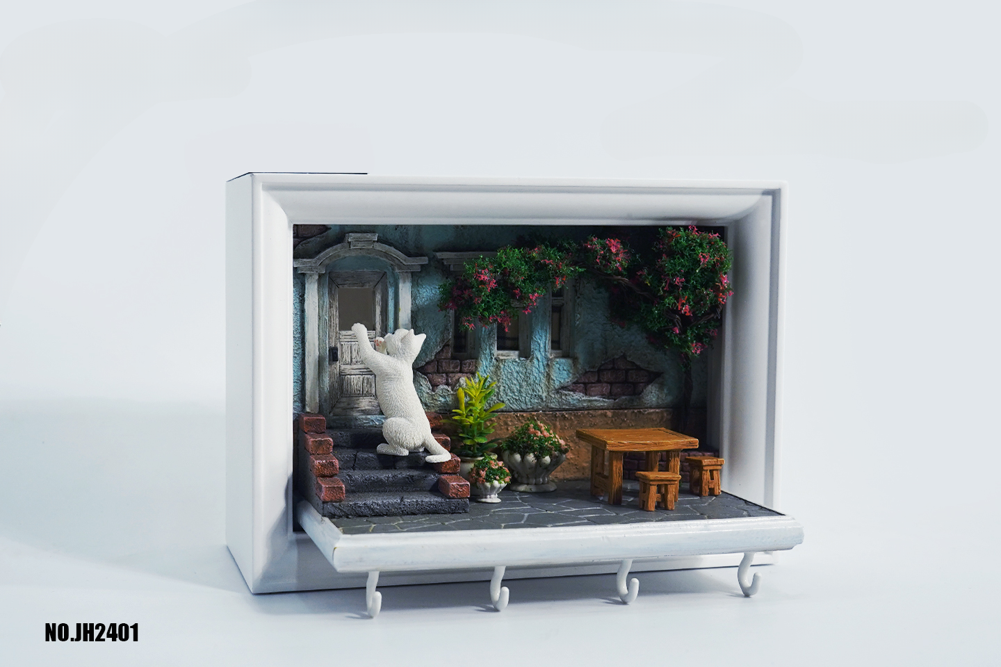 A detailed and charming art relief picture frame model featuring a white cat reaching up towards a window, surrounded by a beautifully crafted miniature garden with flowers, plants, and a rustic table with chairs. Perfect for adding a touch of whimsy and artistic flair to any room.