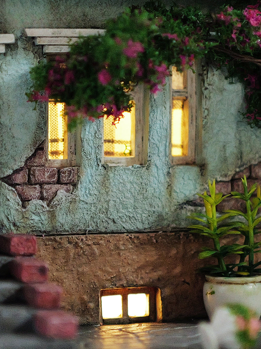 A detailed and charming art relief picture frame model featuring a white cat reaching up towards a window, surrounded by a beautifully crafted miniature garden with flowers, plants, and a rustic table with chairs. Perfect for adding a touch of whimsy and artistic flair to any room.