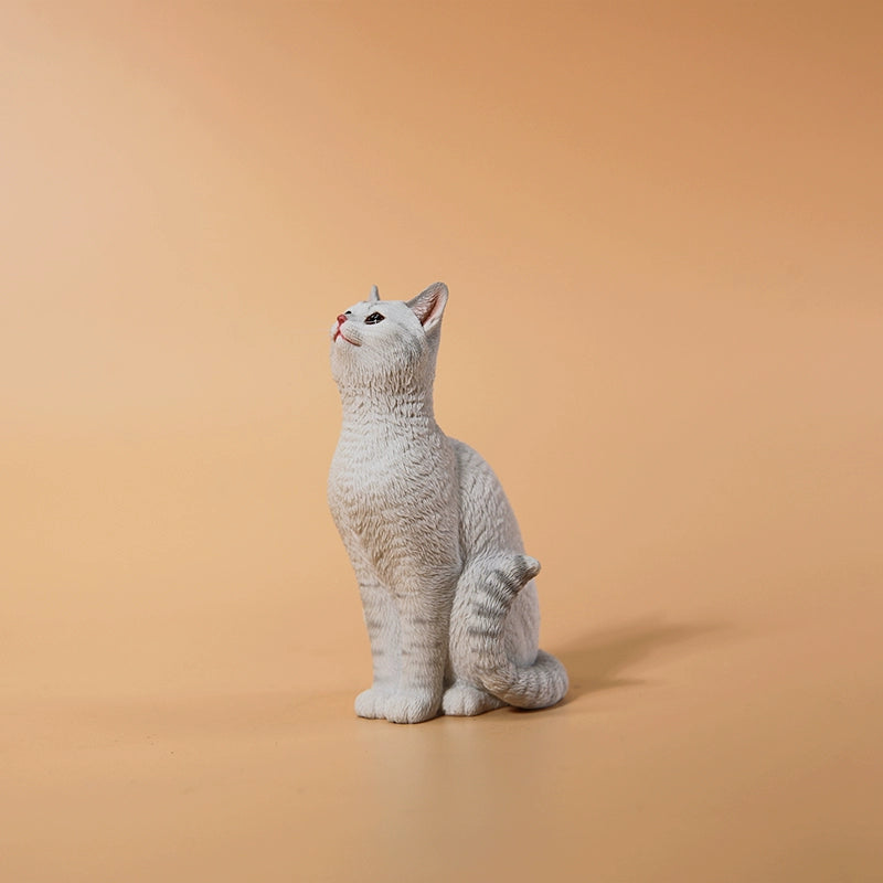 "A 1/6 scale model featuring an orange cat sitting in front of a detailed miniature blue door, adorned with intricate designs. The scene includes a potted plant and a small tree with a lantern hanging from it, capturing a whimsical and cozy setting."