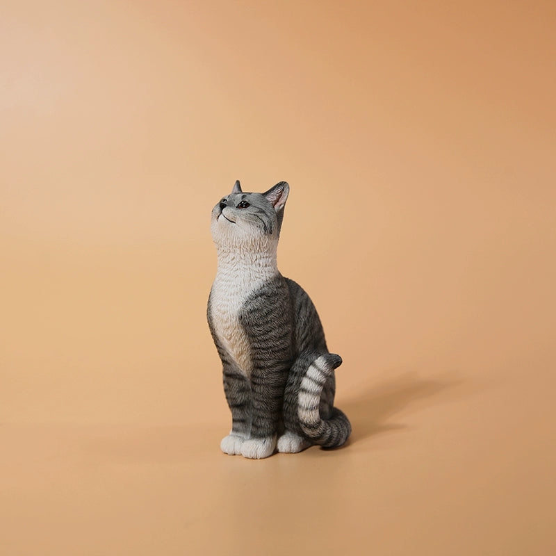 "A 1/6 scale model featuring an orange cat sitting in front of a detailed miniature blue door, adorned with intricate designs. The scene includes a potted plant and a small tree with a lantern hanging from it, capturing a whimsical and cozy setting."