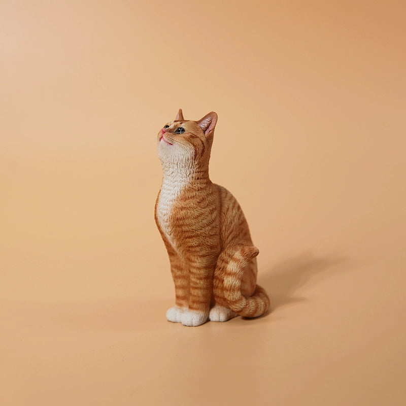 "A 1/6 scale model featuring an orange cat sitting in front of a detailed miniature blue door, adorned with intricate designs. The scene includes a potted plant and a small tree with a lantern hanging from it, capturing a whimsical and cozy setting."