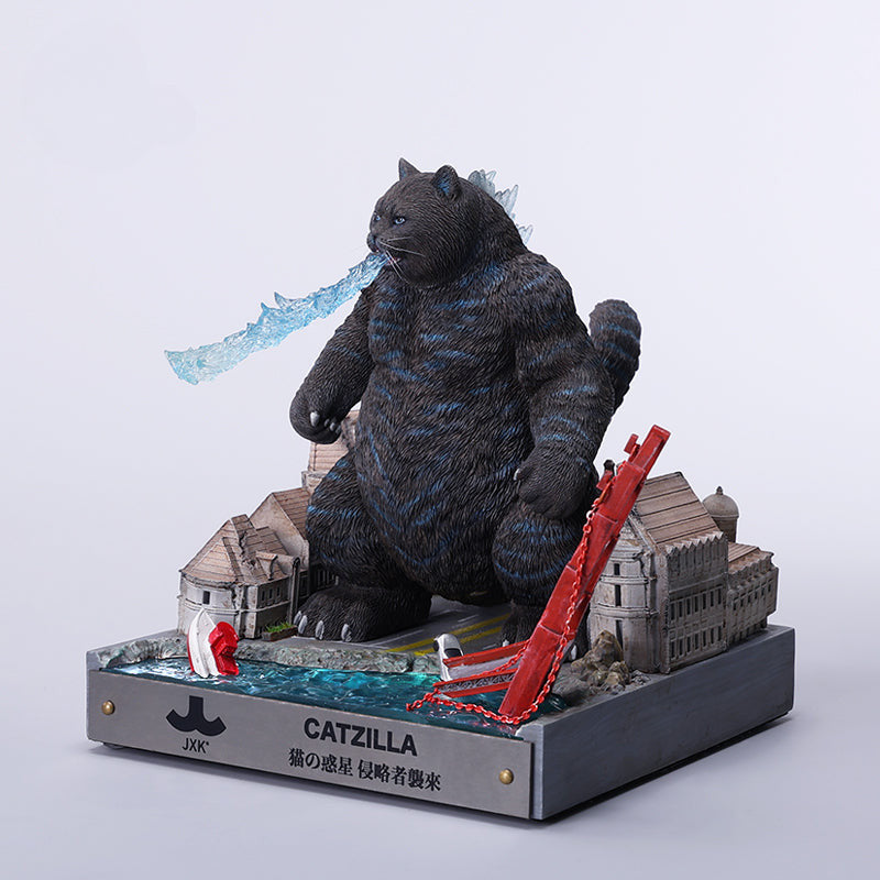 A striking model of Catzilla 2.0, showcasing a large, formidable cat figure breathing blue flames. The cat stands amid a miniature cityscape, featuring detailed buildings and structures, with another image displaying both the orange and black versions of the Catzilla model.