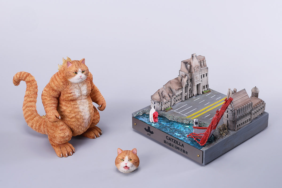 A striking model of Catzilla 2.0, showcasing a large, formidable cat figure breathing blue flames. The cat stands amid a miniature cityscape, featuring detailed buildings and structures, with another image displaying both the orange and black versions of the Catzilla model.