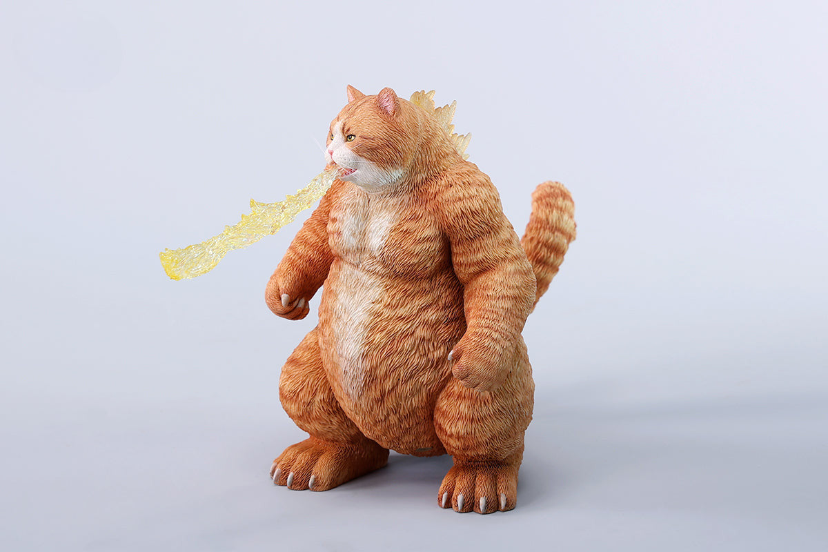 A striking model of Catzilla 2.0, showcasing a large, formidable cat figure breathing blue flames. The cat stands amid a miniature cityscape, featuring detailed buildings and structures, with another image displaying both the orange and black versions of the Catzilla model.