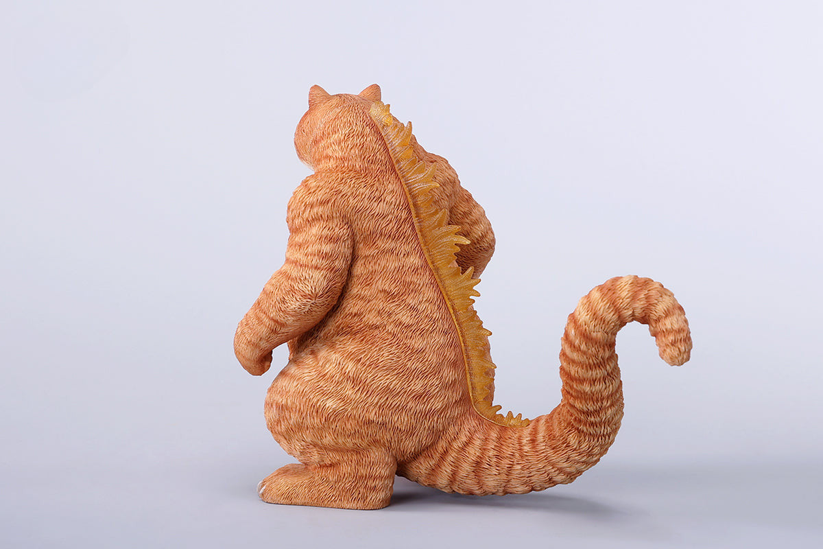 A striking model of Catzilla 2.0, showcasing a large, formidable cat figure breathing blue flames. The cat stands amid a miniature cityscape, featuring detailed buildings and structures, with another image displaying both the orange and black versions of the Catzilla model.