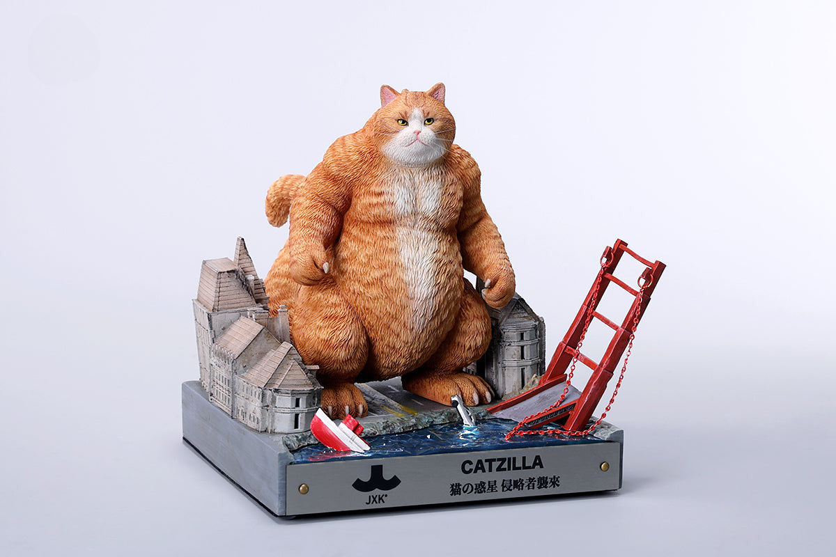 A striking model of Catzilla 2.0, showcasing a large, formidable cat figure breathing blue flames. The cat stands amid a miniature cityscape, featuring detailed buildings and structures, with another image displaying both the orange and black versions of the Catzilla model.