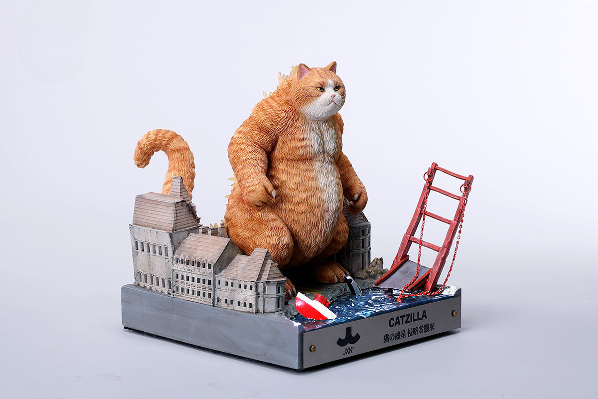 A striking model of Catzilla 2.0, showcasing a large, formidable cat figure breathing blue flames. The cat stands amid a miniature cityscape, featuring detailed buildings and structures, with another image displaying both the orange and black versions of the Catzilla model.