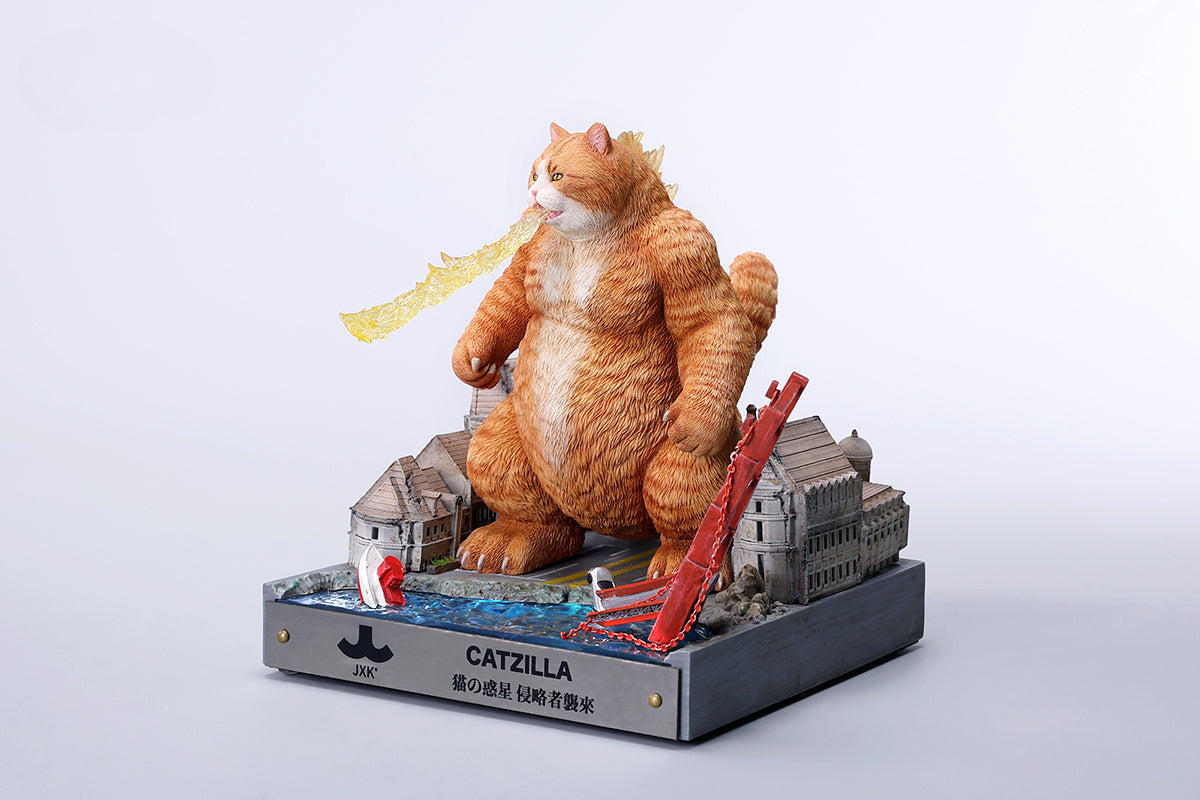 A striking model of Catzilla 2.0, showcasing a large, formidable cat figure breathing blue flames. The cat stands amid a miniature cityscape, featuring detailed buildings and structures, with another image displaying both the orange and black versions of the Catzilla model.