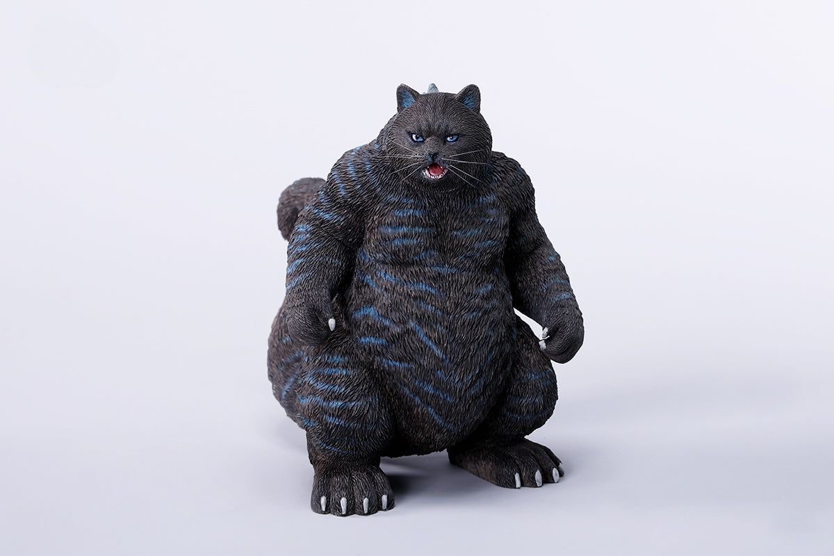 A striking model of Catzilla 2.0, showcasing a large, formidable cat figure breathing blue flames. The cat stands amid a miniature cityscape, featuring detailed buildings and structures, with another image displaying both the orange and black versions of the Catzilla model.