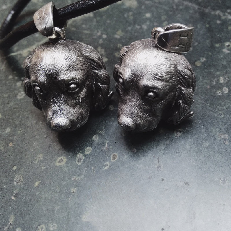 Close-up of a handcrafted Cocker Spaniel pendant in 925 silver, featuring detailed sculpting and gemstone eyes. Available in silver and antique black finishes, with options for custom engraving to create a personalized pet memorial.