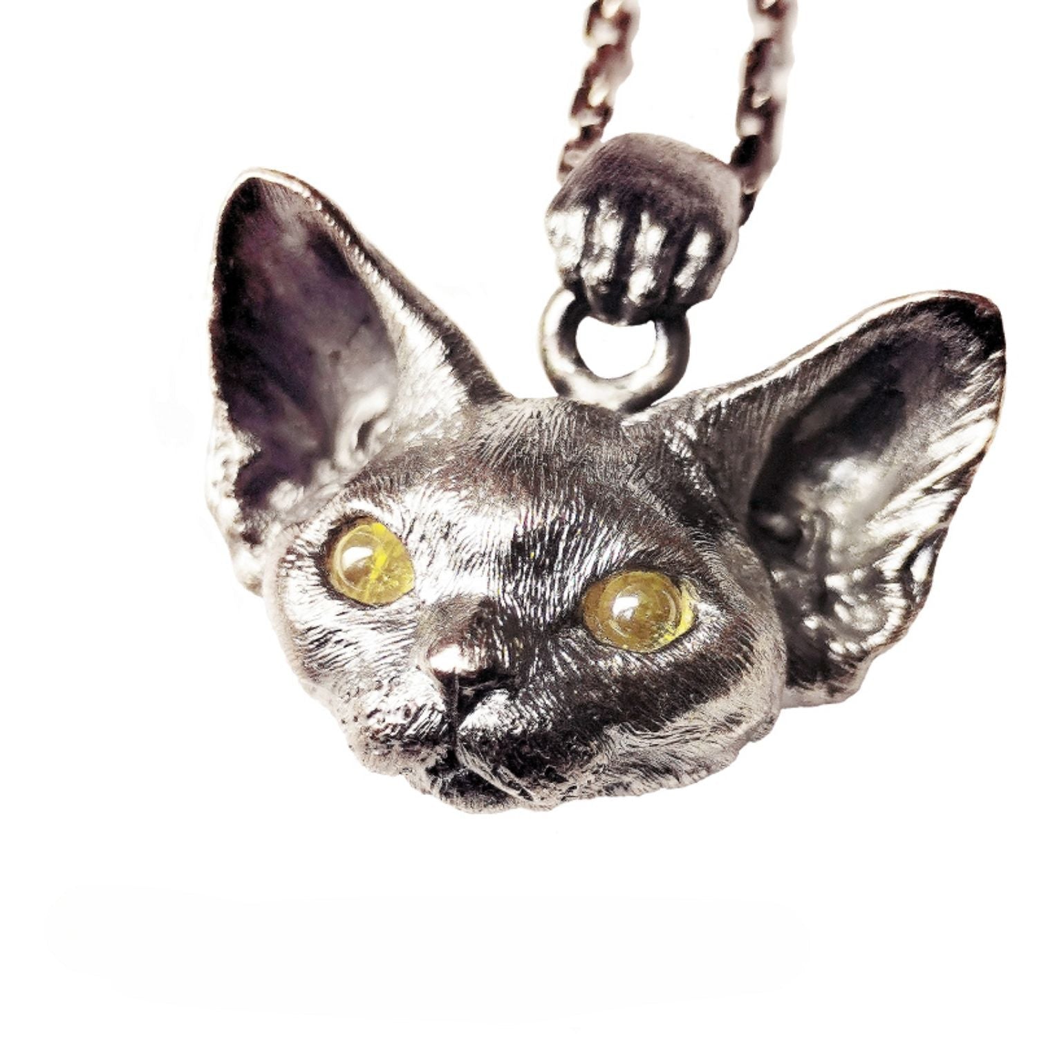 This image showcases the Devon Bobcat Silver Pendant, a beautifully handcrafted pet memorial necklace made from 925 sterling silver. The pendant features lifelike details of the Devon Bobcat, with carefully set gemstone eyes that add a unique touch. Due to the handcrafted nature, each piece has slight variations, making it one-of-a-kind. Custom engraving is available to personalize the pendant as a cherished keepsake. The image highlights the fine craftsmanship and delicate details that make this pendan