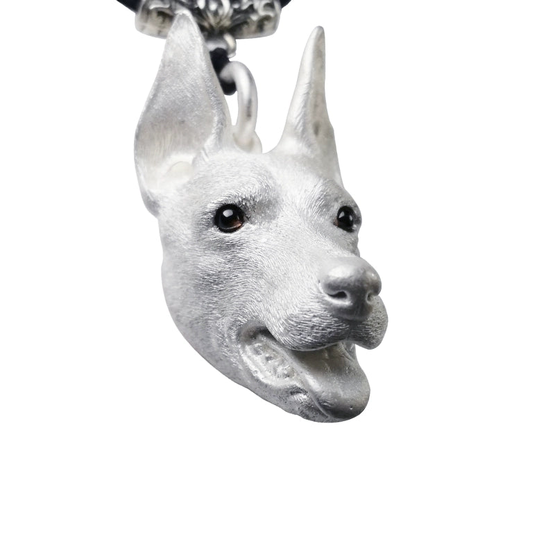 Close-up of a handcrafted 925 sterling silver Doberman pendant, showcasing detailed carving and gemstone inlaid eyes. Available in natural silver and antique black finishes, with customizable engraving options.