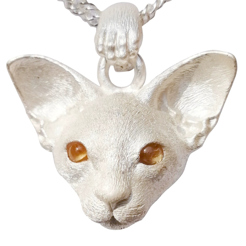 Close-up image of the East Short Abbey Cat Pendant, handcrafted from 925 pure silver with detailed cat features and gemstone eyes. Available in silver and antique black finishes, this pendant can be personalized with custom engraving to honor your pet’s memory.