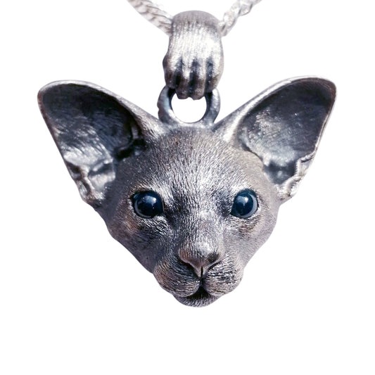 Close-up image of the East Short Abbey Cat Pendant, handcrafted from 925 pure silver with detailed cat features and gemstone eyes. Available in silver and antique black finishes, this pendant can be personalized with custom engraving to honor your pet’s memory.