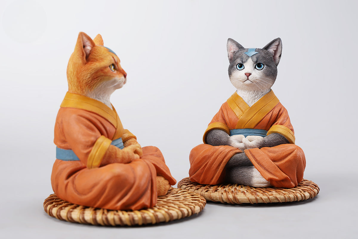 A handcrafted Airbender Cat Figurine in a meditative pose, dressed in an orange robe with a blue sash, sitting on a rattan-weaved cushion. This finely detailed resin sculpture captures the tranquility of mindfulness, perfect for cat lovers and meditation enthusiasts. An ideal collectible and decorative accent for any serene space.