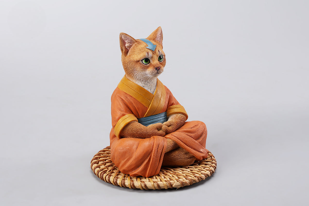 A handcrafted Airbender Cat Figurine in a meditative pose, dressed in an orange robe with a blue sash, sitting on a rattan-weaved cushion. This finely detailed resin sculpture captures the tranquility of mindfulness, perfect for cat lovers and meditation enthusiasts. An ideal collectible and decorative accent for any serene space.